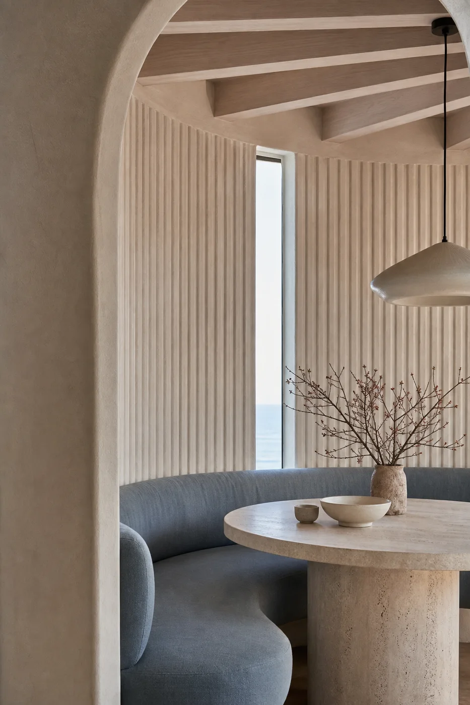 Sculptural coastal interior with curved plaster, ribbed walls, and muted blue seating