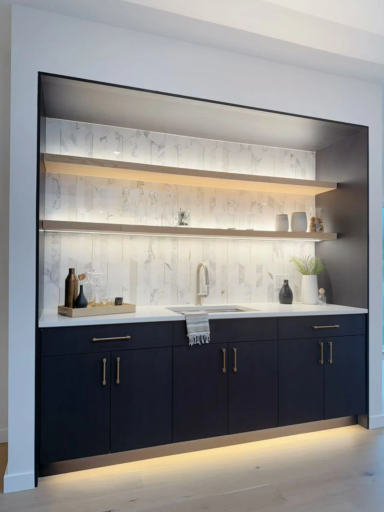 Completed navy cabinet project with an illuminated marble backsplash